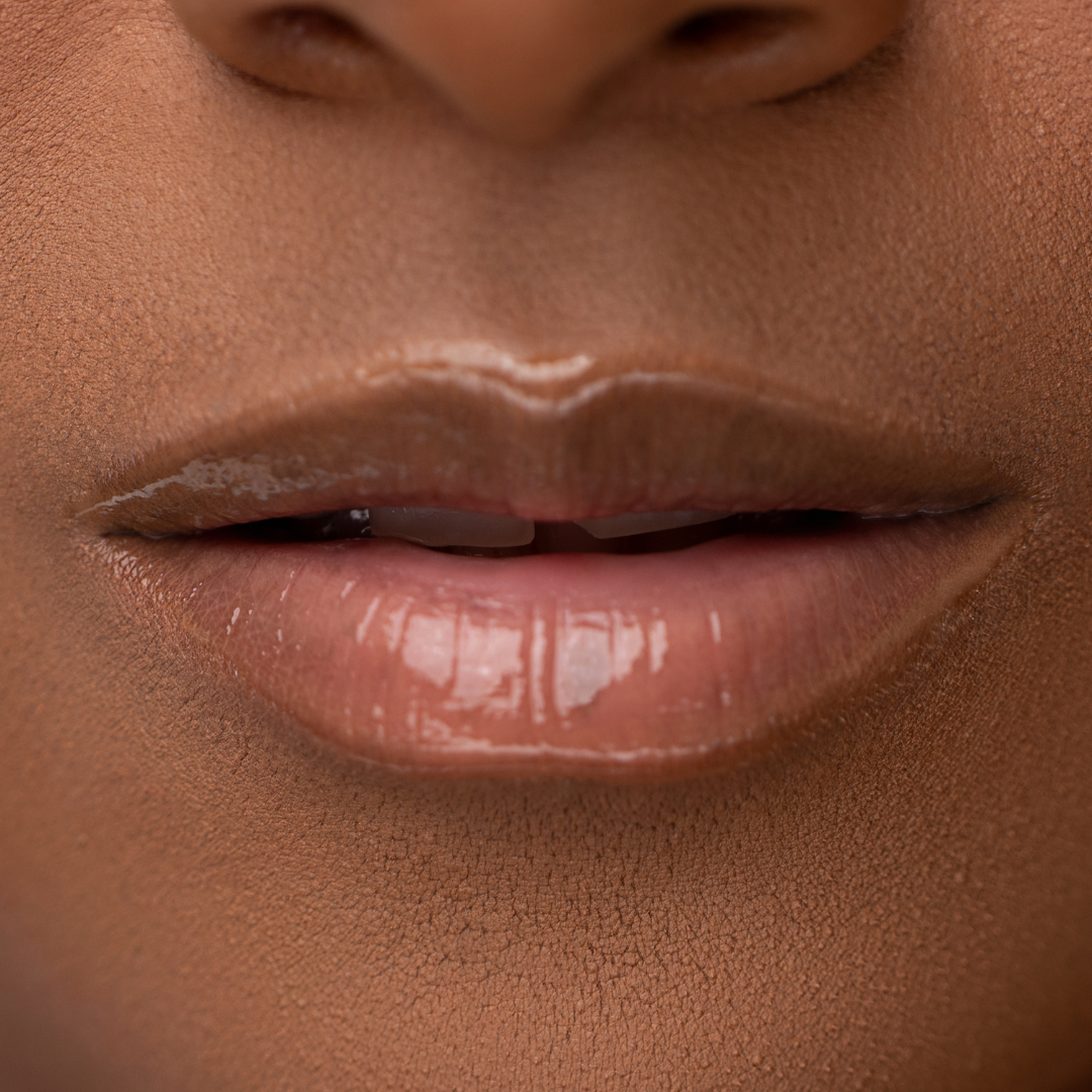 Close-up of LippEase Tinted Lip Treatments C-Thru showing glossy high shine finish on medium skin tone. Neutral Brown Liner Lip Combos