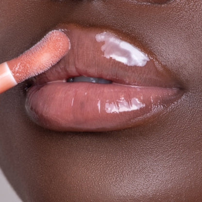 Lip model shot of nude Halo Glow Lip Oil applied over medium-deep skin tone – radiant glass finish with hydrating glow.
