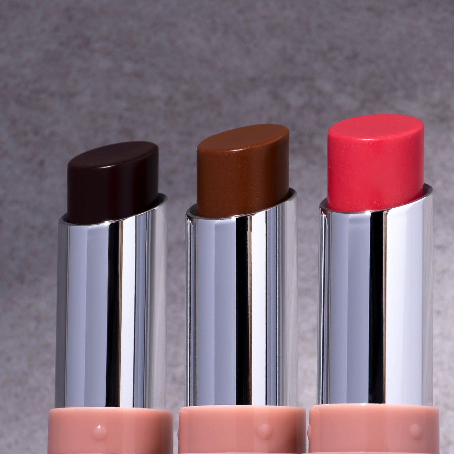 “Flat-lay of Lumi Balm Lip Tint tube in shades Beauty Sleep, Fantasy, and Dream – editorial studio lighting emphasizing the brand’s message: ‘Confidence is Beauty’”