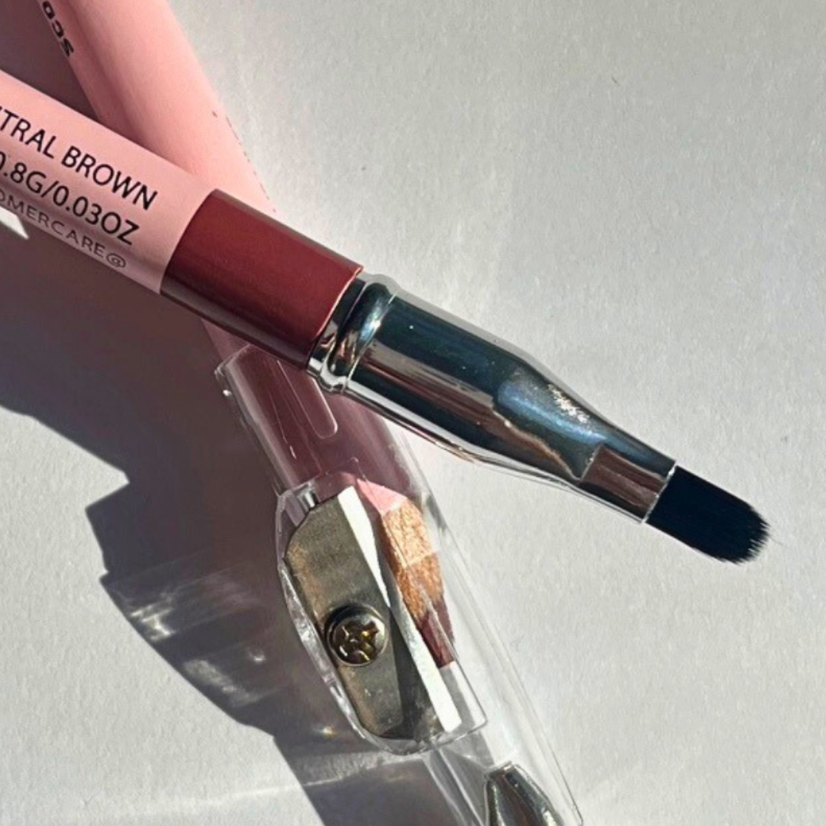 Pink Lipps Neutral Brown Lip Liner styled flat-lay with clear sharpener and blending brush – clean studio lighting