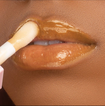 Lip model shot of golden Vanilla Sky Glow Lip Oil applied over medium skin tone – radiant glass finish with hydrating glow.