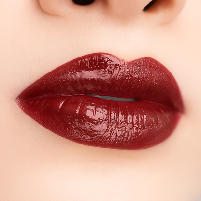 Swatch of Bold Lip Gloss shade ‘Burgundy’ on fair skin tone – deep wine red with mirror-shine finish
