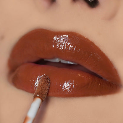Lip-on model shot: Brown Suga Nude Glass Gloss applied on light to deep skin tone — pigmented high-shine finish