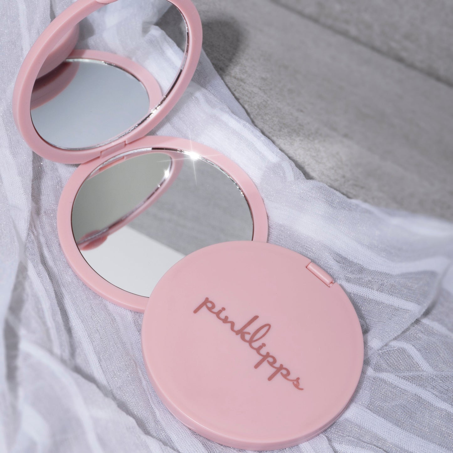 Double-Sided Mirror showing a pink, compact design with dual reflections, ideal for beauty on the go.