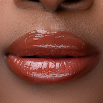 Close-up of LippEase Tinted Lip Treatments Mood showing glossy warm chocolate high shine finish on deep skin tone 