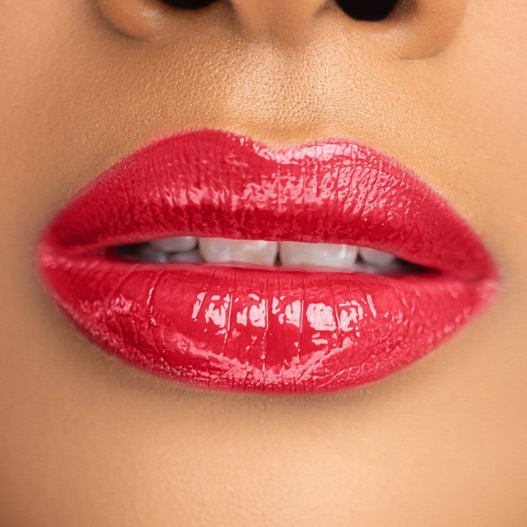 Swatch of Bold Lip Gloss shade ‘Red’ on melanin skin tone – classic cherry red gloss that flatters every complexion