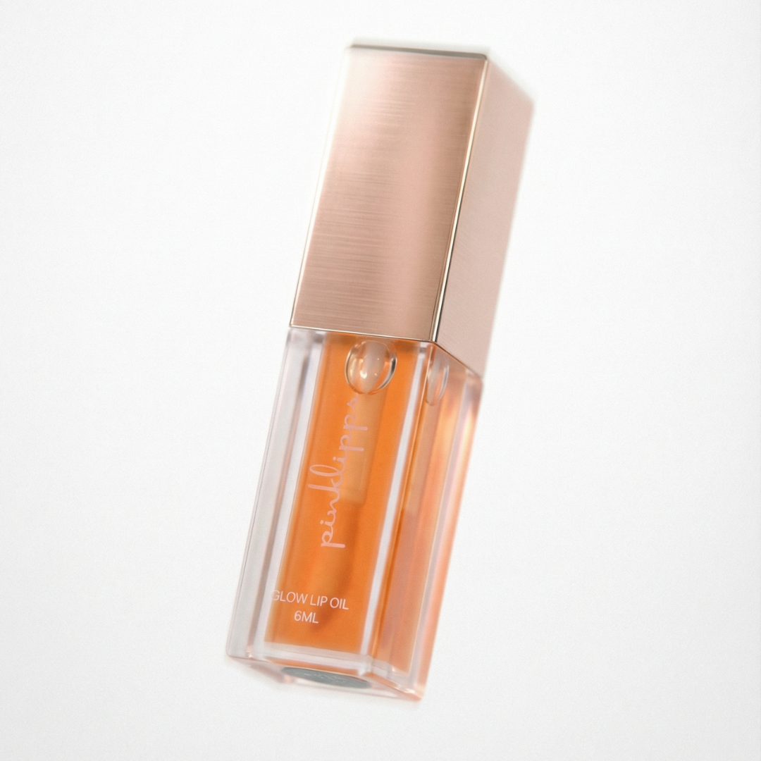 Pink Lipps 'SunGlow' Glow Lip Oil tube on white background, oranges scent vegan high-shine orange lip oil for every shade of melanin.