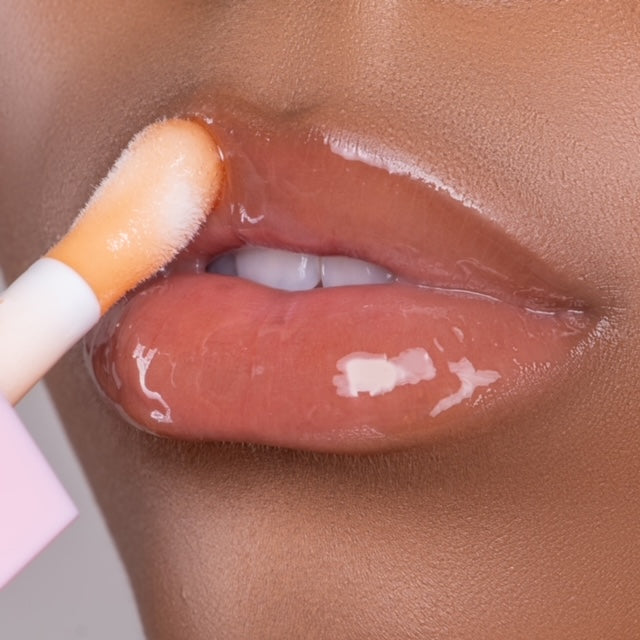 Lip model shot of orange SunGlow Glow Lip Oil applied over medium skin tone – radiant glass finish with hydrating glow.
