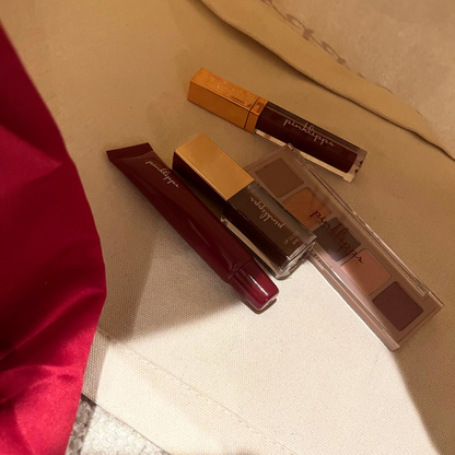 Pink Lipps Tote Bag lifestyle flat-lay with burgundy lipstick, lip balm and eyeshadow — tan neutral bag with burgundy straps styled on light background